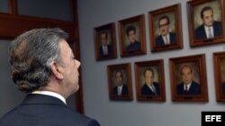 Juan Manuel Santos mira las imágenes de los magistrados de la Corte Suprema de Justica que murieron durante la toma del Palacio de Justicia. EFE